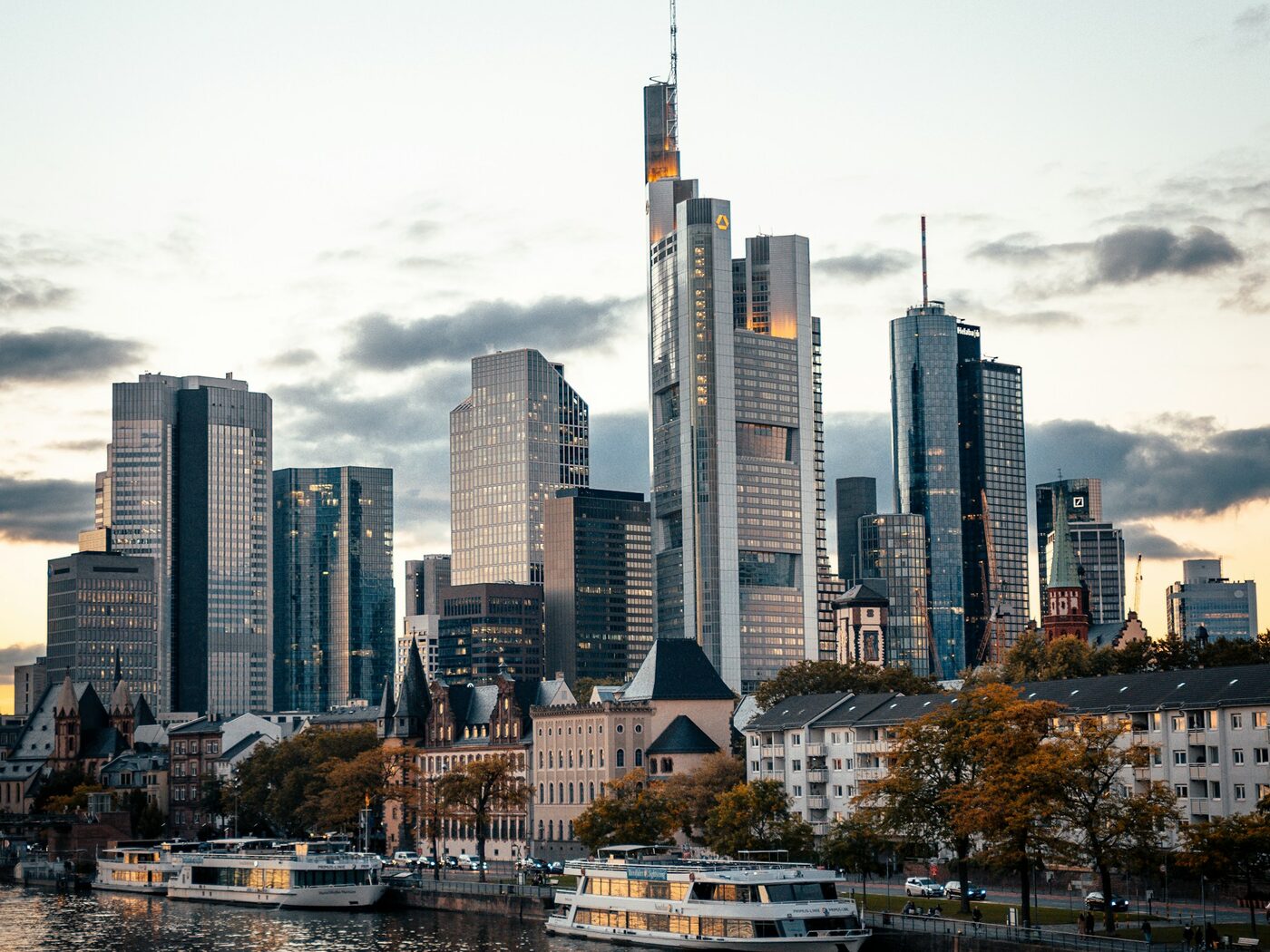 Skyline des Frankfurter Bankenviertels am Main mit Ausflugsschiffen in der Abenddämmerung